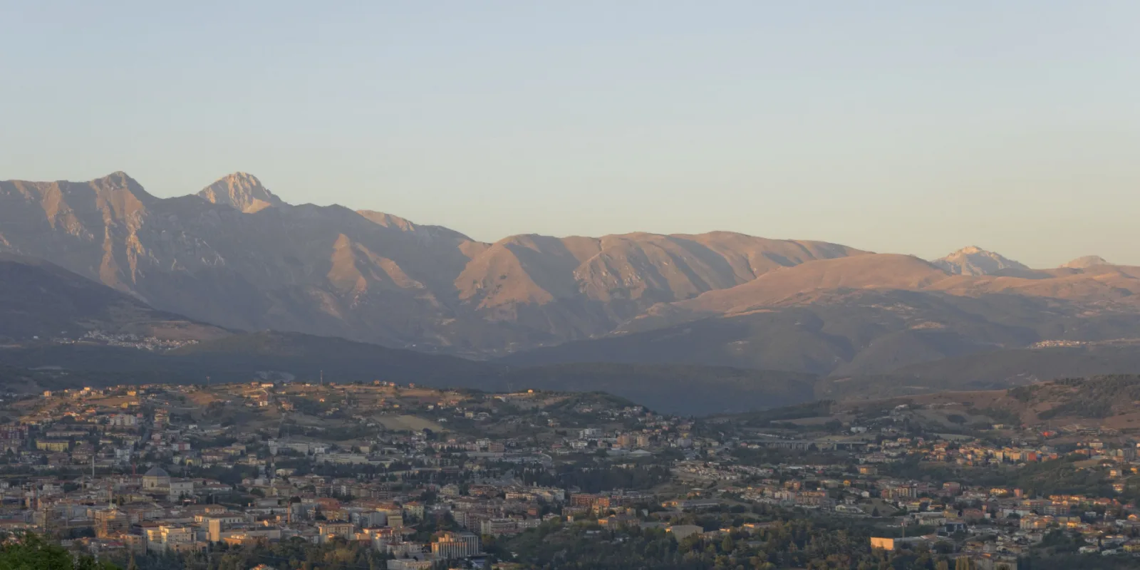 Panorama dell'Aquila con il massiccio del Gran Sasso sullo sfondo al tramonto